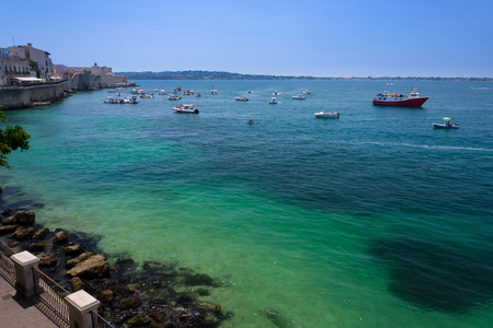 Boats coast the island of Ortigia in the Mediterranean Sea, Syracuse, Italyの写真素材