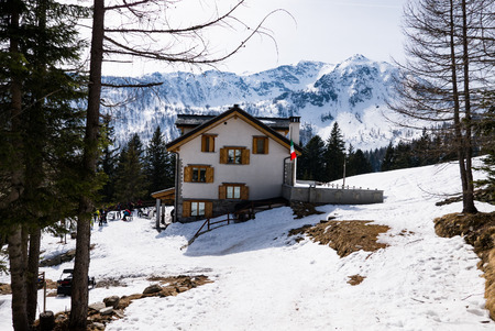 Excursions make a stop at a mountain refuge with the Italian flag in a snowy landscape, Italyのeditorial素材