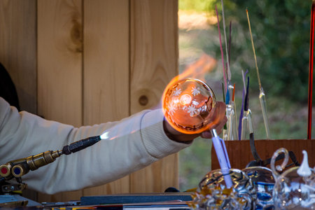 Glassblower handling the glass ball with a gas burner, italy