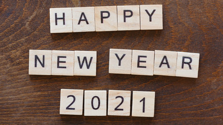 written happy new year 2021 with light wood letters on dark wood