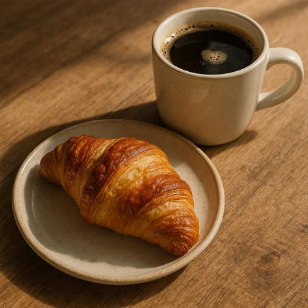 Cup of coffee and croissant on wooden table, breakfast concept