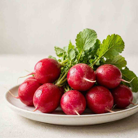 Bunch of fresh red radishes with green leaves on white background.