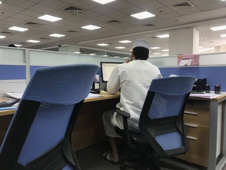 Oman national arab national employee working under pressure in over time in an corporate office to finish the work before the dead line assigned by her strict boss to avoid the firing of jobの写真素材