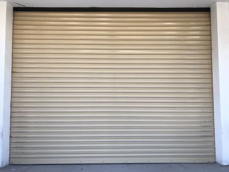 Beige color Mechanic or Hydraulic operated rolling shutter for an shop or garage or storage yard of an building and this is front entrance undulated sheet for more security purposeの写真素材