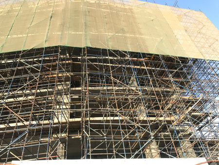 Construction project is in under progress and green safety net is around the building to avoid...