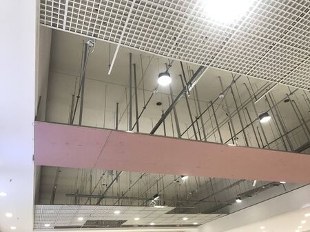 Macro Grid False ceiling around gypsum finished under progress which expose pink gypsum board furring channels supports and threaded rod