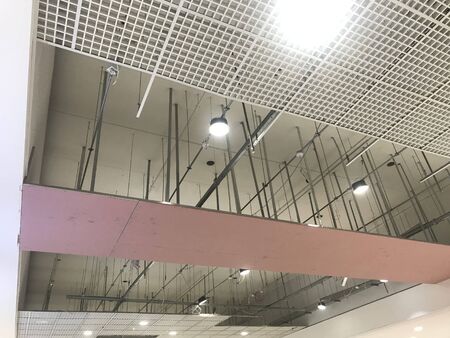 Macro Grid False ceiling around gypsum finished under progress which expose pink gypsum board furring channels supports and threaded rod