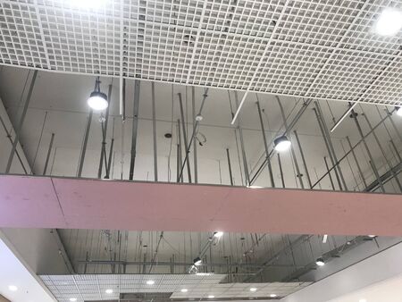 Macro Grid False ceiling around gypsum finished under progress which expose pink gypsum board furring channels supports and threaded rod