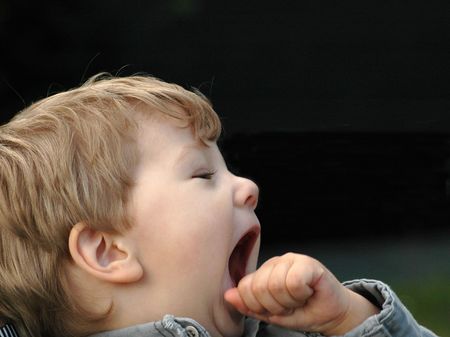 A child yawns. He is tired and wants to sleep.の写真素材