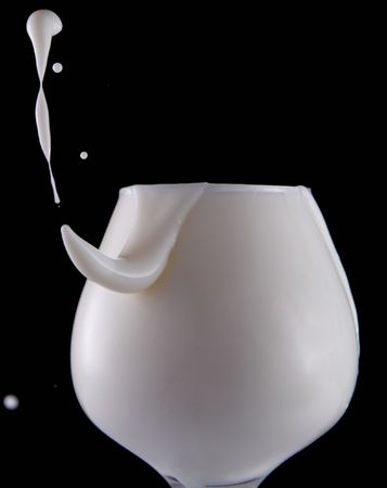 Splash milk in the glass on the black backgroundの写真素材