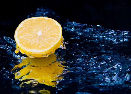 Lemon and splash water over black backgroundの写真素材
