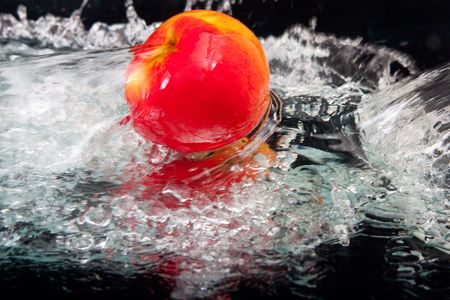 Apple and splash water over black backgroundの写真素材