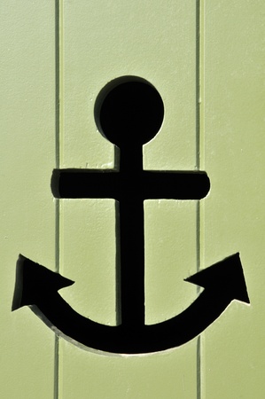 Black marin anchor perforated in a green doorの写真素材