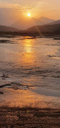 Sunset view with sun reflection in water pools after rain, Sultanate of Omanの写真素材