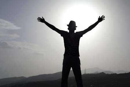 Freedom and travel A man raises his hands with a mountain backgroundの写真素材