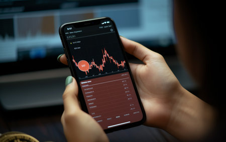 Woman is checking bitcoin price chart on digital exchange on smartphoneの素材