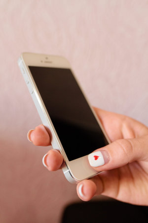 white gadget smartphone in the hands of a girl with a blue T-shirt