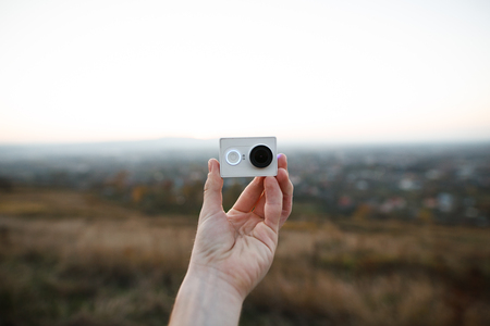 human hands holding an action camera on the sunset backgroundの写真素材