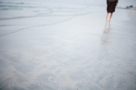 A beautiful girl is walking along the shore against a beautiful sunsetの写真素材