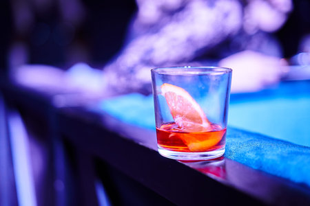 Glass with alcoholic refreshing on a bar table and background color light