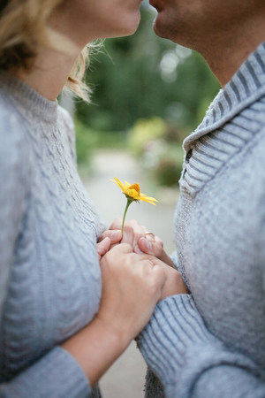 Girl and man hold yellow flower together and look at each otherの写真素材