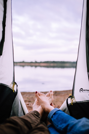 Legs of people in a tent on the background of a fire and the riverの写真素材