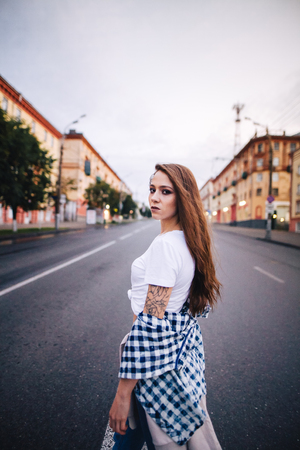 The girl turned around in the middle of the roadway. Girl in a plaid shirt and jeans.の写真素材