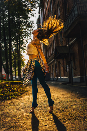 Hair stylish girls develop in the light of dawn. City Style. Girl in a white top and sweatpants.の写真素材