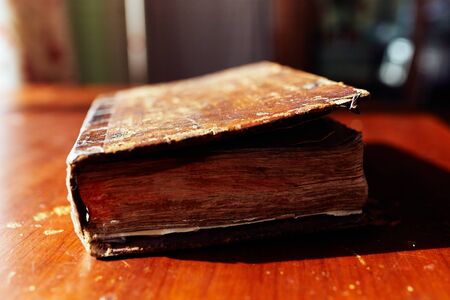 Old volumetric closed book on a wooden table on a sunny dayの写真素材