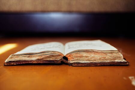 Old voluminous book with ancient text on a wooden tableの写真素材
