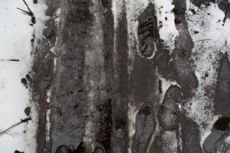 Groung melting snow mud dark gray brown puddleの写真素材