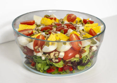 Salad with quartered egg, tomato, lettuce, and grains in a bowlの写真素材