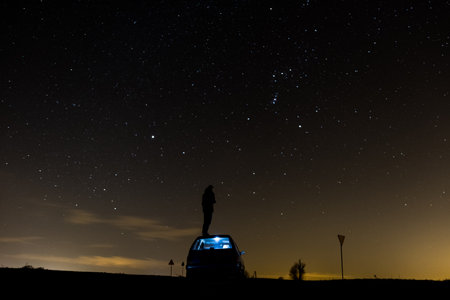 A man standing on a car in the background of stars with a night sky, a shining galaxyの写真素材