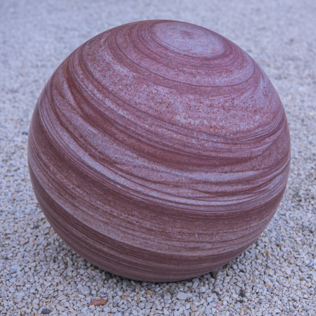 marbled stone sphere standing alone on pebble stoneの写真素材
