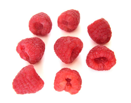 Eight raspberries on white table
