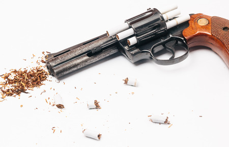 Revolver loaded with cigarettes to symbolize the dangers of smokingの写真素材