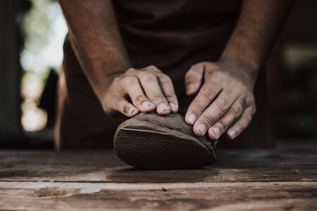 Craftsman hands close up, kneads and moistens the clay before work.の写真素材