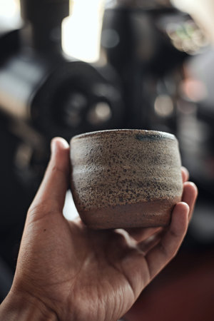 Hand holding a cup of coffee on blur background.