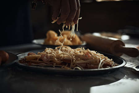 A closeup of hand making an Italian pizza on a floured surface.の写真素材