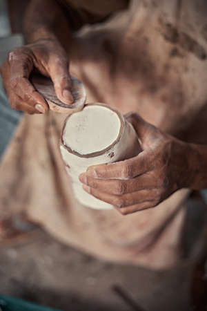 the artist polishing rough edges of a ceramic pot with a sponge in pottery studio.の写真素材