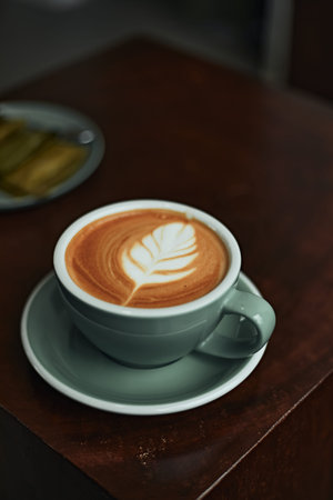 Selective focus cup of hot latte art coffee on wooden table,focus at white foam