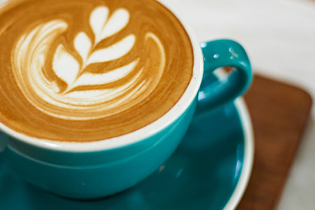 Selective focus cup of hot latte art coffee on wooden table,focus at white foamの写真素材