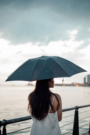 Silhouette  woman holding umbrella in the rain at sea, selective focusの写真素材