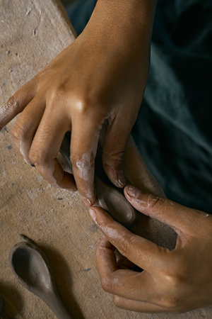 Close up of hands shaping a small clay spoonの写真素材