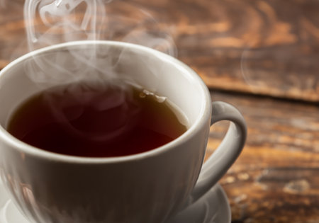 Hot steaming black tea in a cup on a rustic backgroundの素材