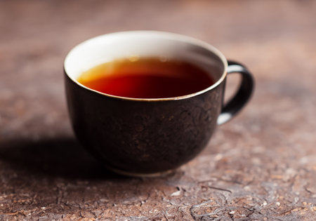 Hot steaming black tea in a cup on a rustic backgroundの素材