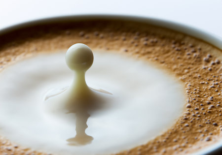 Drops of coffee with milk fall in a glass of milk, high speedの素材