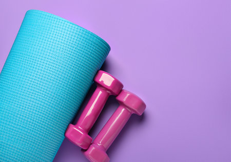 Yoga mat and dumbbells on purple background.の素材