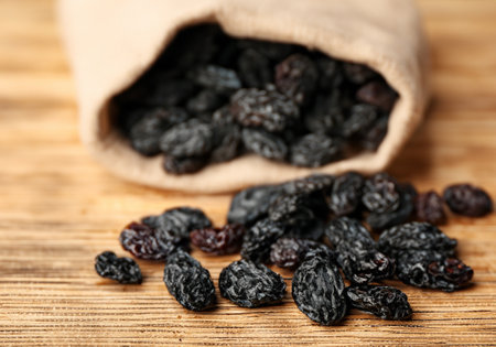 Black raisins in burlap bag over wooden tableの素材
