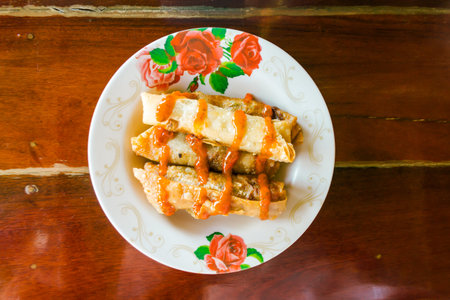 Spring rolls and sauces on wooden table, selective focus